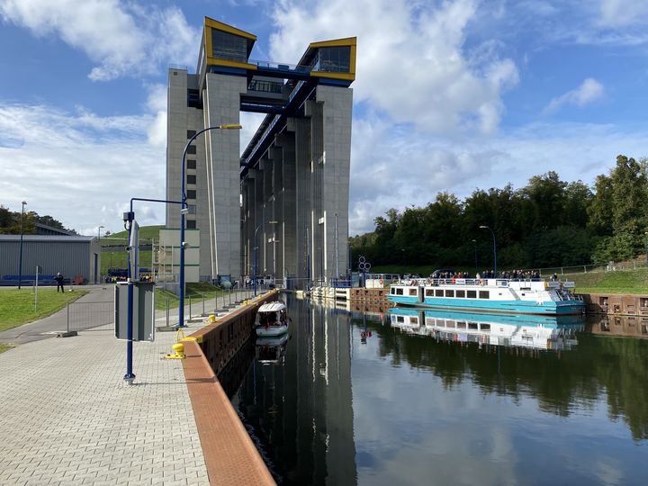 Front view of the new Niederfinow ship lift with a passenger vessel and a small boat in the basin in front of the structure.
