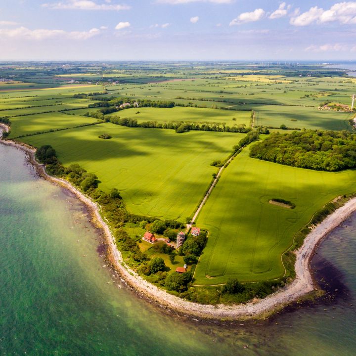 Aerial view of the island of Fehmarn with green fields, wooded areas and coastline along the Baltic Sea.